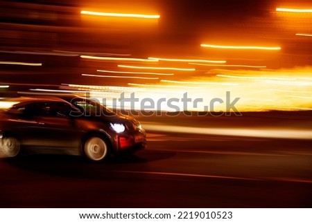 compact car at speed on the street with nighttime light trails Royalty-Free Stock Photo #2219010523