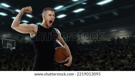 Win, goal, success. Excited young professional basketball player shouting at basketball court with people fans. Photoreal 3d render of sport arena with spot lights. Concept of sport, energy, power