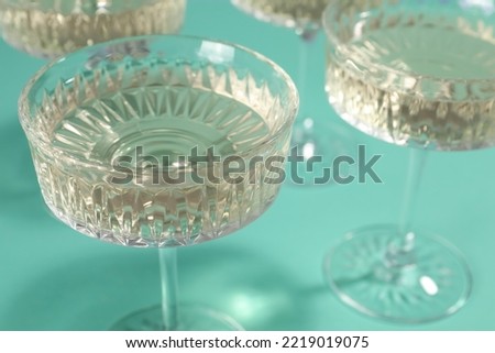 Glasses of expensive white wine on turquoise background, closeup