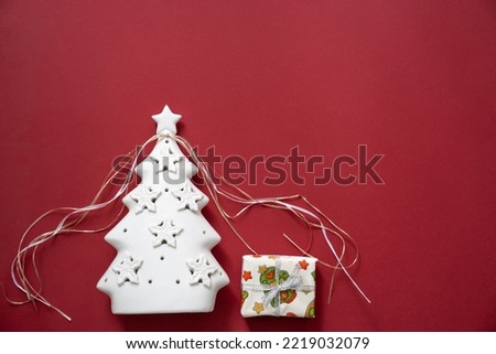 wrapped gift box under christmas tree on a red background, festive holidays magic