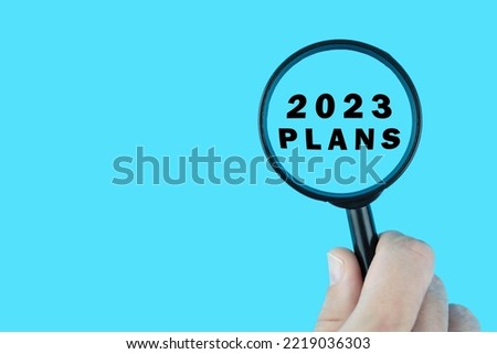 Focused on plan for next year 2023 concept. Words 2023 plans under magnifying glass. Card design.
