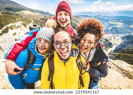 Multiracial group of young people hiking mountains together - Happy friends taking selfie picture on the top of the cliff - Trekking, travel and sport concept