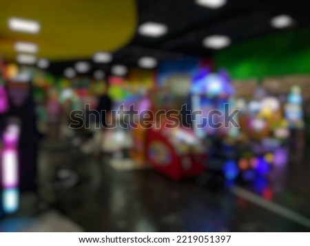Defocused abstract background of arcade game machine in departement store. Dark Bokeh image of the game zone for background usage.