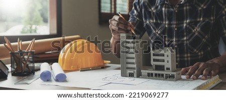 Image of engineer drawing a blue print design building or house, An engineer workplace with blueprints, pencil, protractor and safety helmet, Industry concept