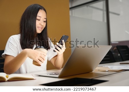 Charming business analyst with smart phone is reading message in modern office
