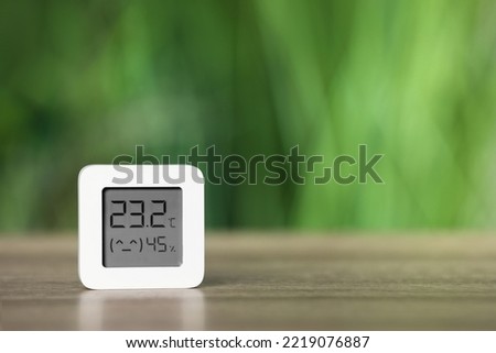 Digital hygrometer with thermometer on table against blurred background. Space for text Royalty-Free Stock Photo #2219076887