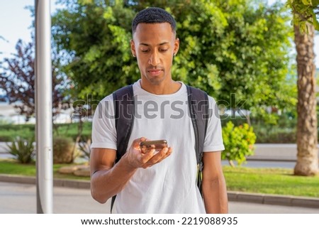 Side view of young african american man smiling happy using smartphone at street of city.