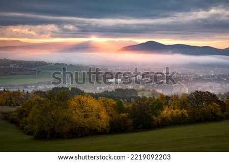 Foggy fall morning near Banska Bystrica. Landscape with forests and mountains around the city. Autumn colored trees at sunrise. Royalty-Free Stock Photo #2219092203