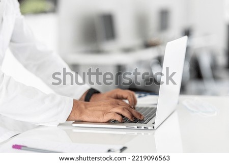 Close up of a doctors hands typing on laptop