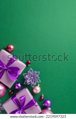Christmas concept. Top view photo of lilac gift boxes with purple ribbon bows pink violet baubles and flower ornament on isolated green background with blank space