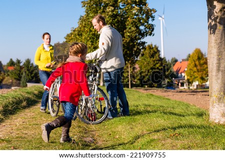 Family with mother, father and daughter having family trip on bicycle or cycle in park or country