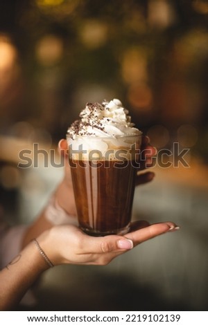 Coffee with whipped cream and chocolate chips in the hands of a girl Royalty-Free Stock Photo #2219102139