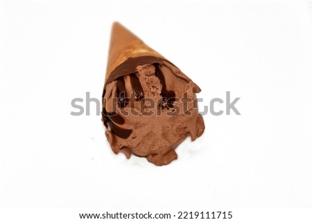 Chocolate vanilla ice cream ball on a biscuit cone with chocolate sauce isolated on white background, selective focus of dark brown ice cream cone with a melting chocolate
