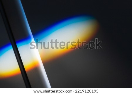 Sunbeam with spectrum colors lays over white wall, refraction effect. Abstract background photo