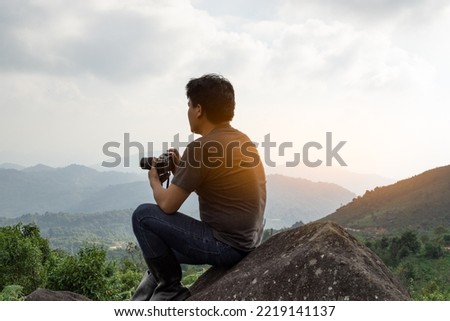 An Asian man catching camera travel alone at mountain and look at far a way, nature travel and environment concept computer sunrise light, copy space for individual text