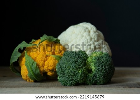 white cauliflower and orange cauliflower on wooden floor
