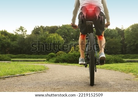 Problem of injured coccyx. Man riding bicycle on road