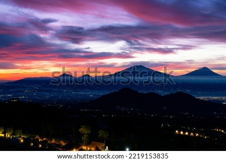 Beautiful colorful epic sunrise sky with mountain range and beautiful city lights, Magelang City and Merapi, Merbabu, Andong, Telomoyo mountain looking out from Sumbing Mountain - Mangli Village