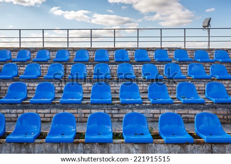 Empty blue plastic chairs at a football stadium