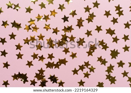 Golden confetti stars on color background, top view.