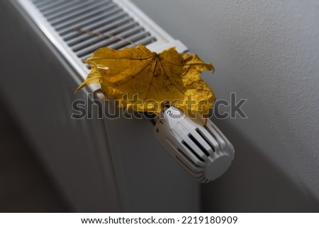 Heating battery with autumn leaf on white background. The concept of saving.