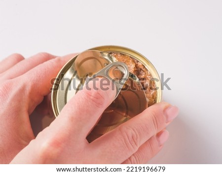 Man's hands opening a aluminum can full of cat or dog food, pate, grinned meat for pet food. Recycle materials, ecological Royalty-Free Stock Photo #2219196679