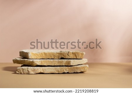 Background with an empty stack of stones on a beige background. Stone podium for cosmetic products. Pedestal for product presentation.