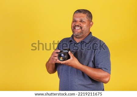Brazilian black man, adult holding photo camera, photography hobby, photographer.