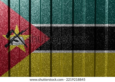Textured flag of Mozambique on metal wall. Colorful natural abstract geometric background with lines.
