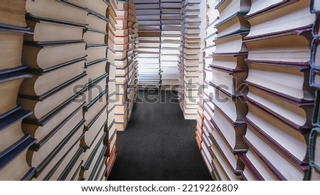 Stacks of books in the form of a long corridor. Wide angle view. Abstract books, library, learning and wisdom theme image Royalty-Free Stock Photo #2219226809