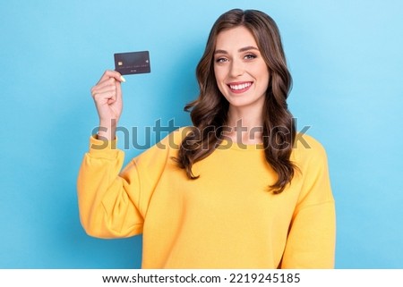 Photo of young attractive pretty gorgeous woman wear yellow swetshirt hold credit card toothy smile beaming recommend bank isolated on blue color background