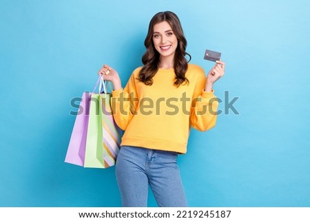 Photo portrait of charming young girl hold shopping bags credit card payment wear trendy yellow clothes isolated on blue color background