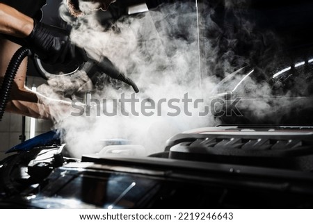Process of steam cleaning car engine from dust and dirt. Steaming washing of motor of auto in detailing auto service Royalty-Free Stock Photo #2219246643