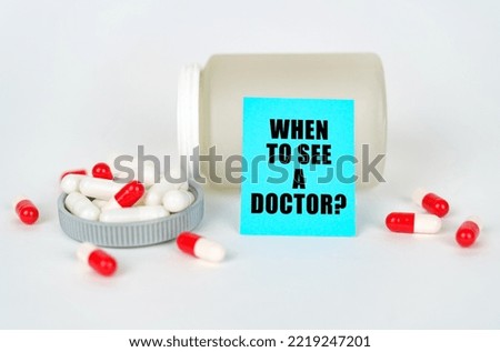 Medical concept. On a gray background, a jar, capsules and a sign with the inscription - When to see a doctor
