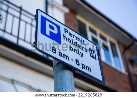 Permit holders only parking restriction sign, black text on white with white on blue P 'parking' symbol