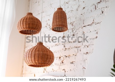three rattan chandeliers different forms on white brick wall background. Straw lampshade in cozy living room. Eco-friendly interior design using natural materials. Scandinavian interior. copy space. Royalty-Free Stock Photo #2219267493