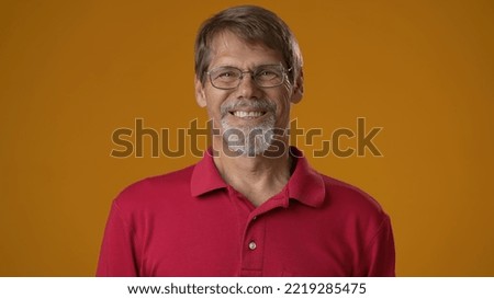 Smiling bearded mature man 50s 60s years old wearing red shirt isolated on solid yellow background studio. People sincere emotions lifestyle concept. Looking camera.