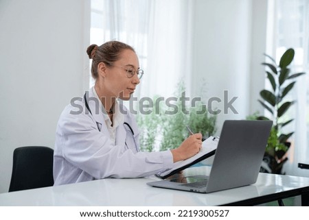 Woman doctor in uniform greeting patients online on laptop during on line meeting.	