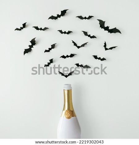 Contemporary layout made with white and gold Champagne bottle with bats silhouettes.
Trendy  composition on white background.
Halloween party concept.
Creative art minimal aesthetic.