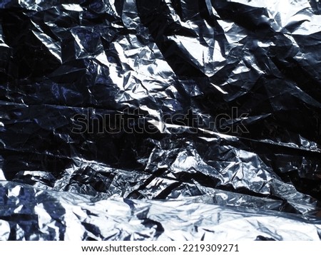 Silver wrinkled plastic sheet in dark for abstract background.