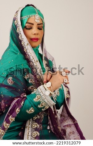 Omani woman wearing traditional clothes and jewelry looking at hand  Royalty-Free Stock Photo #2219312079