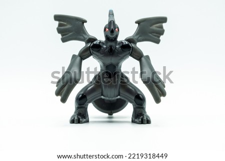 Scary black monster toy with wings and red eyes on white background.