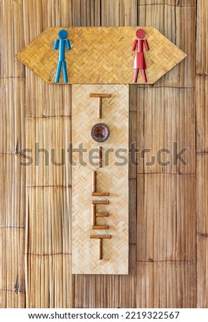 A bathroom sign depicting a man in blue, a man and a pink woman.  Made of woven bamboo  It is a beautiful design design in a simple, local style.