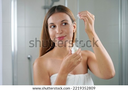 Portrait of a young woman applying Retinol on her face at home. Skin care routine. Royalty-Free Stock Photo #2219352809