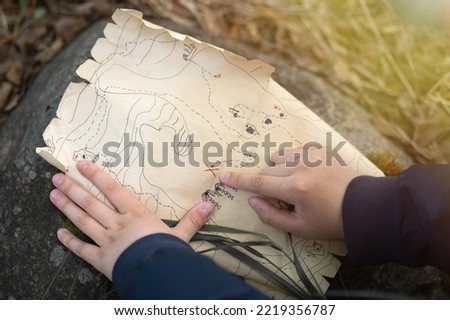 Pirate treasure map for kids.A family treasure hunting game. Outdoor games for the whole family. A treasure hunt quest. The child's hand points to the place with the treasure. Royalty-Free Stock Photo #2219356787