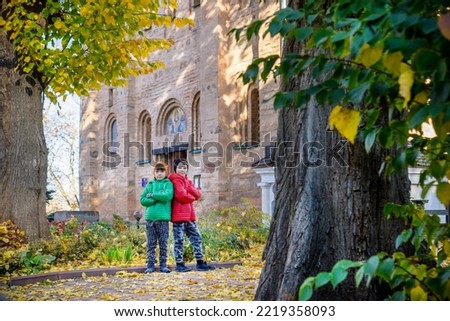 Young brothers near an ancient stone church. Kids smiling and happy having leisure time on autumn holiday. Travel with children concept.