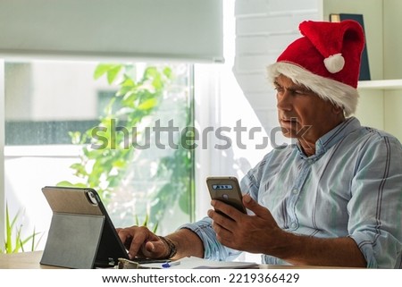 man with santa claus hat and mobile phone in the office or workplace