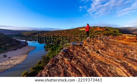 long-haired girl walks along a ridge on the red rocks of kalbarri national park in western australia; hiking in the wilderness, australian outback Royalty-Free Stock Photo #2219373461