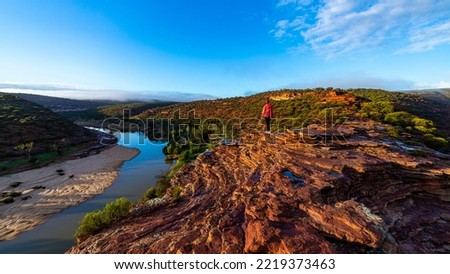 long-haired girl walks along a ridge on the red rocks of kalbarri national park in western australia; hiking in the wilderness, australian outback Royalty-Free Stock Photo #2219373463