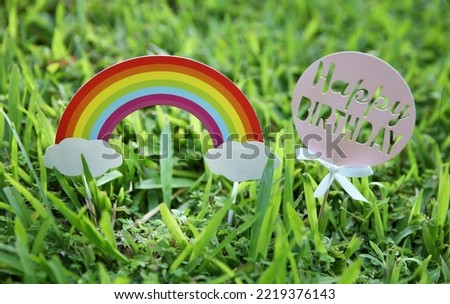 Happy Birthday text on paper card decoration on grass background